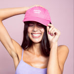 Woman wearing a pink cap with 'Sunday Mode' text on a light pink background