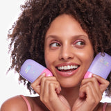 Woman holding two bottles of Naked Sundays CabanaMilk Mineral Barrier Fluid SPF50 with a white background