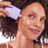 Woman applying sunscreen to her face with a purple bottle labeled 'CabanaMilk'