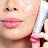 Close up of a person applying lip balm to their lips with a focus on the product