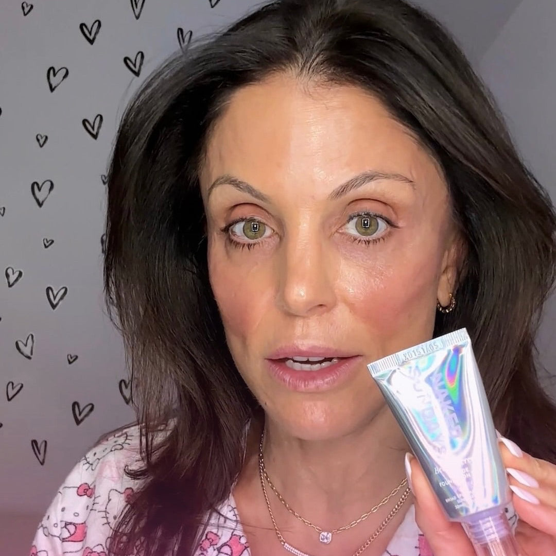 Bethenny Frankel holding a Naked Sundays BeautyScreen tube with a heart patterned background.