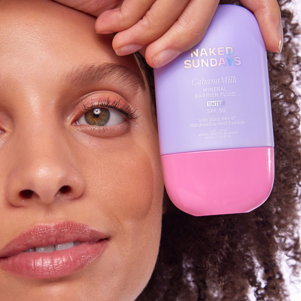 Person applying Naked Sundays CabanaMilk Mineral Barrier Fluid to their face.