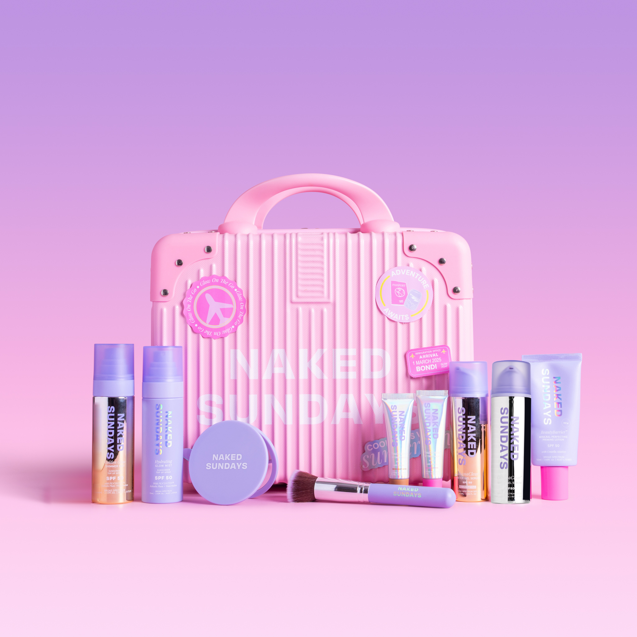 A pink ribbed cosmetic travel case with a handle, decorated with stickers and the words 'NAKED SUNDAYS' in white, surrounded by matching pink and purple beauty products on a pink to purple gradient background