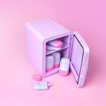 Lilac cosmetics fridge with pink and lilac Cabanamilk SPF50 bottles on a pink background