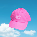 Pink cap with 'Sunday Mode' text against a blue sky with clouds