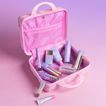 Pink makeup suitcase with various cosmetic products on a pink background