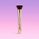 Makeup brush with gold handle on a gradient purple background
