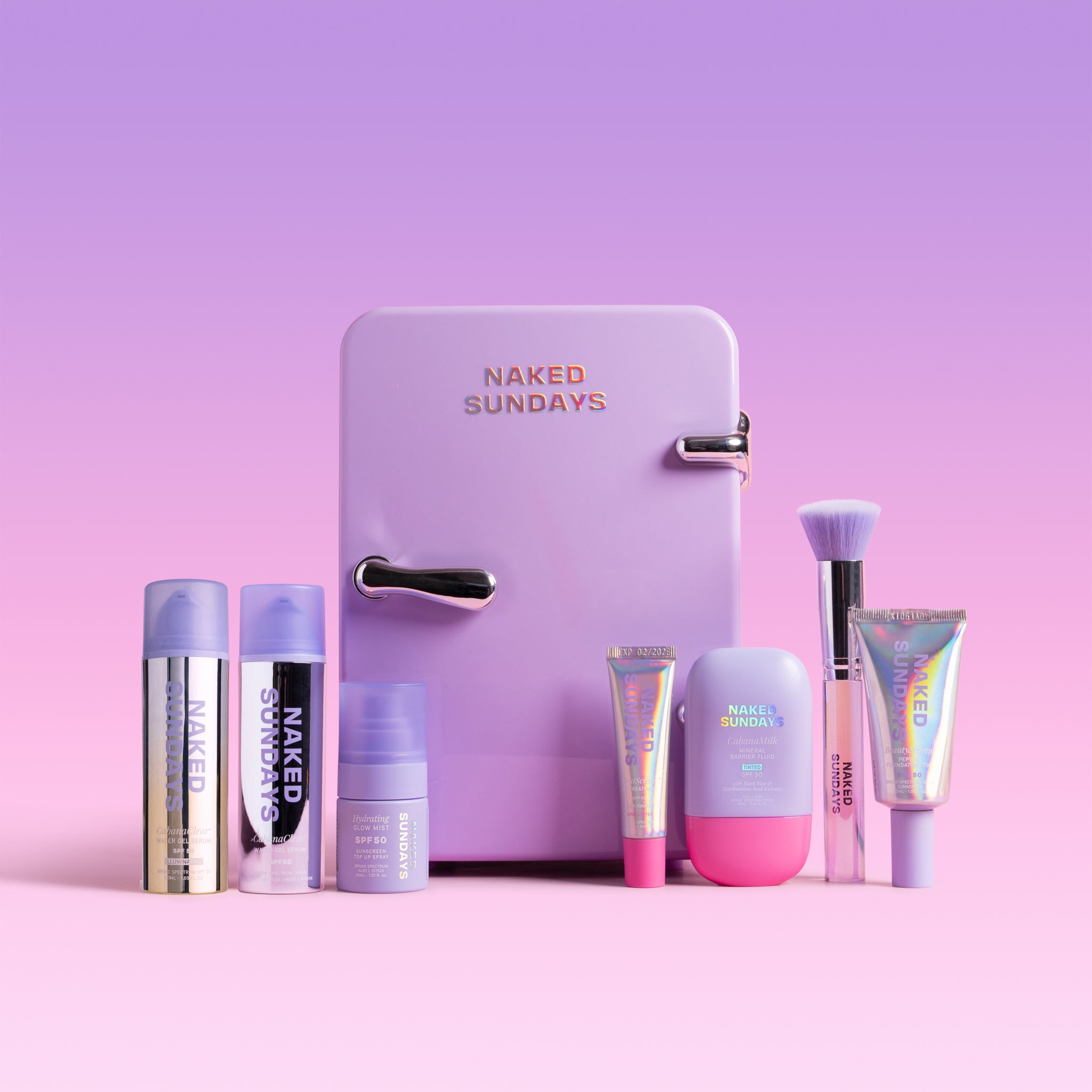 Collection of 'Naked Sundays' skincare products in front of a small refrigerator on a pink background