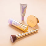 SPF Makeup products including BeautyScreen, CabanaClear in Illuminating, a gold compact mirror, and a gold brush with 'Naked Sundays' branding on a beige background