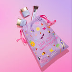 Naked Sundays CabanaGlow Serum Drops and Mini SPF BFF Brush spilling out of a 'Hot Girl Sunscreen' drawstring bag on a gradient background