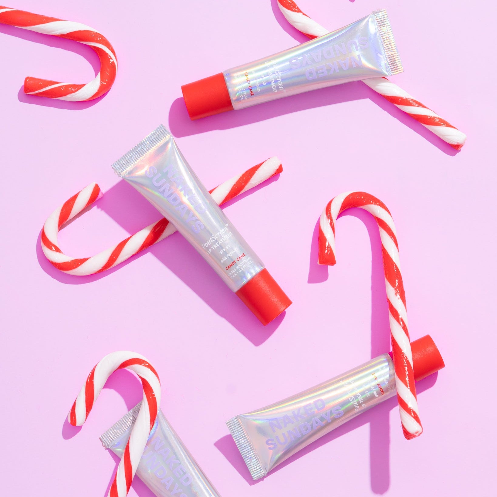  4 lip products with the label Naked Sundays Candy Cane, scattered around a pink background with candy canes