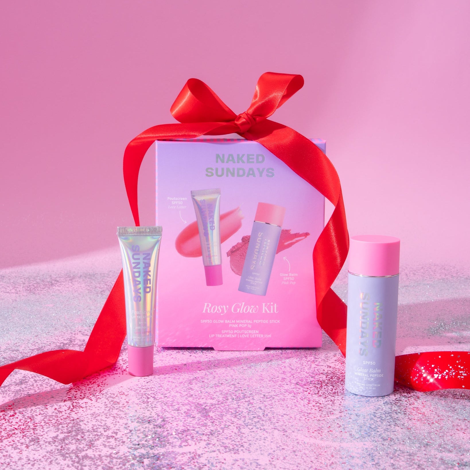 Naked Sundays Rosey Glow Kit Gift Set featuring a lip gloss and cheek stick with SPF on a glittery background