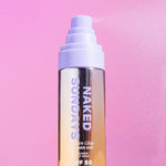Naked Sundays Golden Glow Shimmer Mist spraying to the right, on a pink background