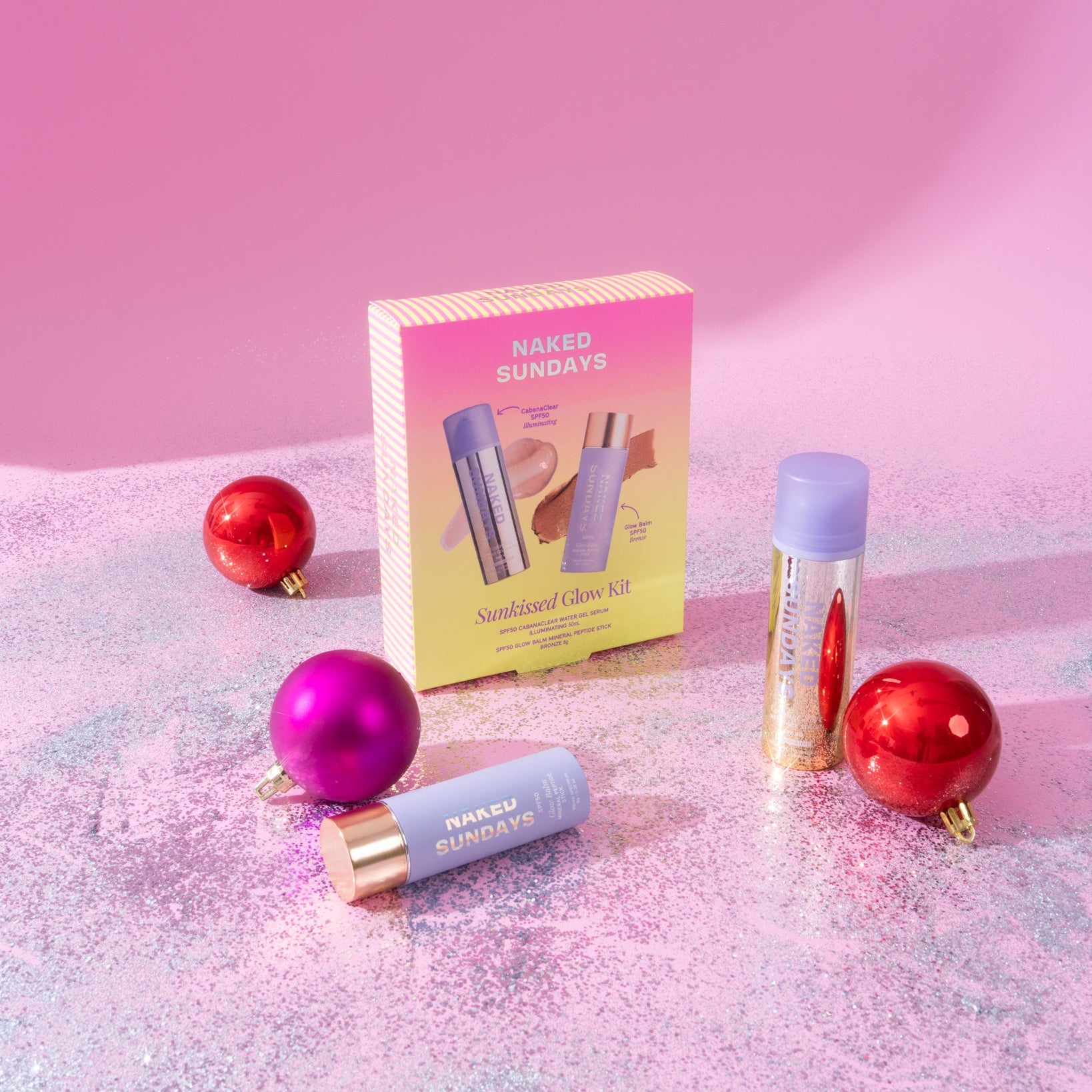 A line up of products from the Naked Sundays Holiday SPF Collection on a glittery surface