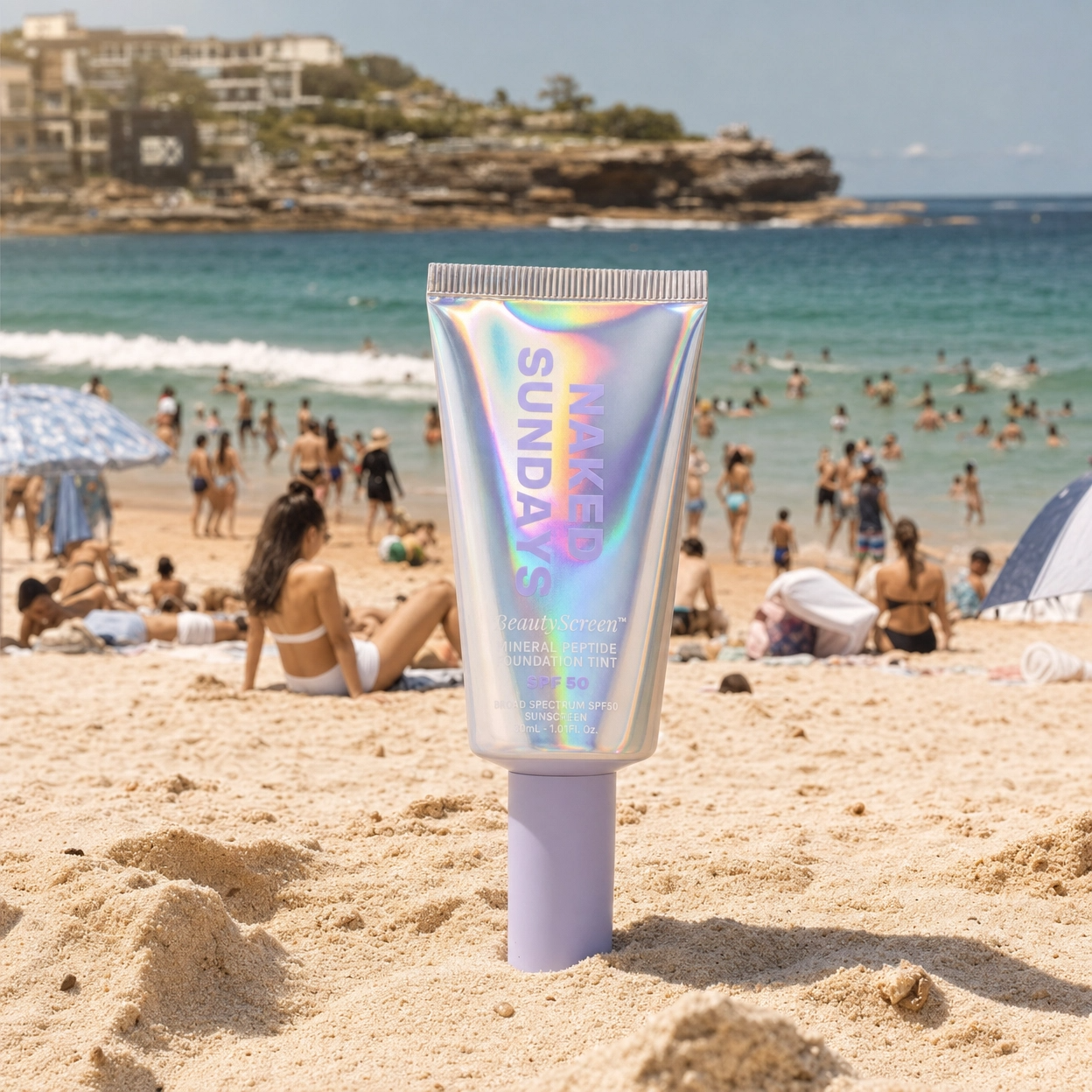 BeautyScreen SPF50 Tint Tube on a sandy beach with people and ocean in the background
