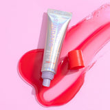 A tube of Naked Sundays Lip SPF and a red swatch of product on a pink background