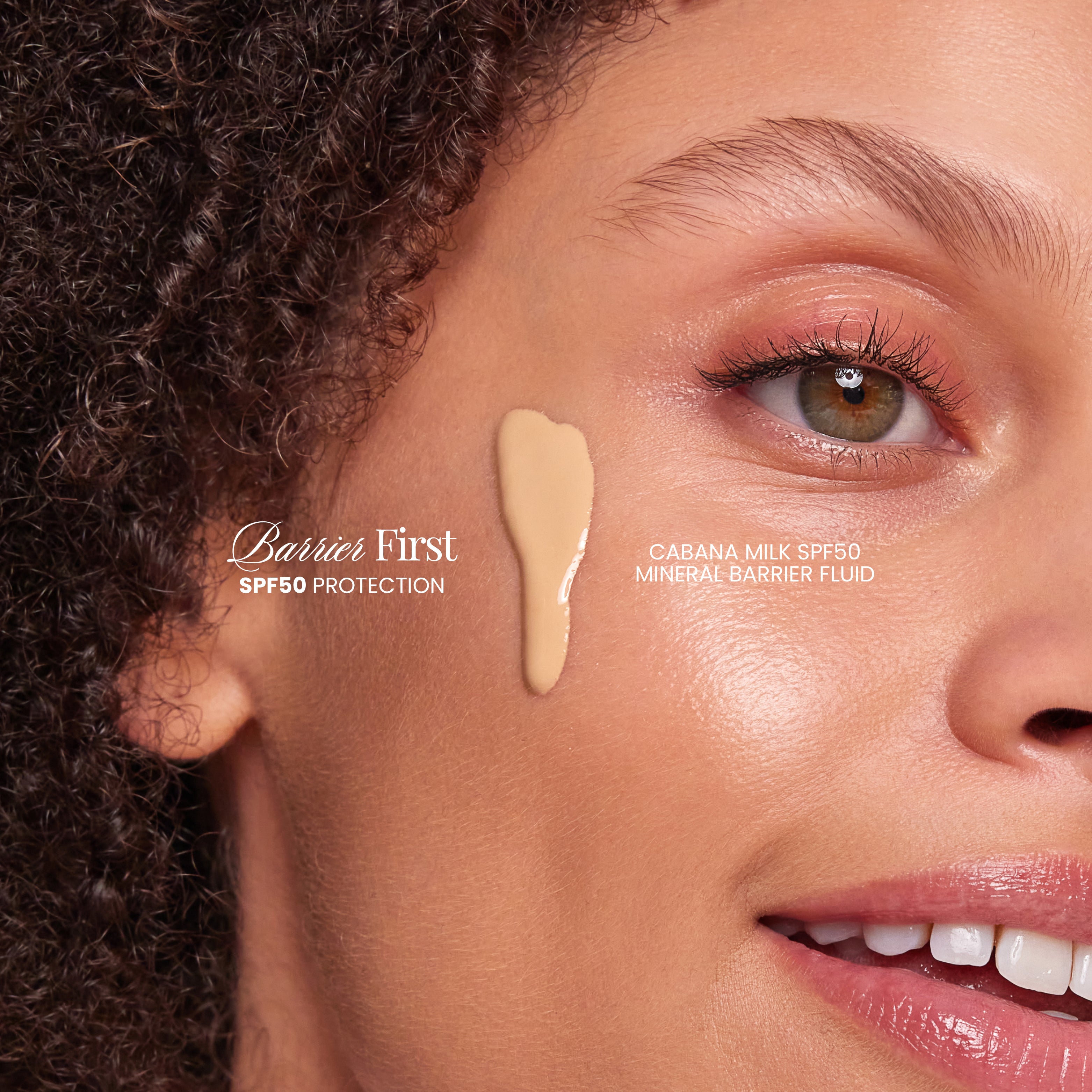 Close-up of a woman's face with a droplet of Barrier First SPF50 protection product on her cheek.