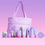 A pastel purple makeup bag with long handles sits on a pink lavender studio background, surrounded by matching cosmetic products from Naked Sundays